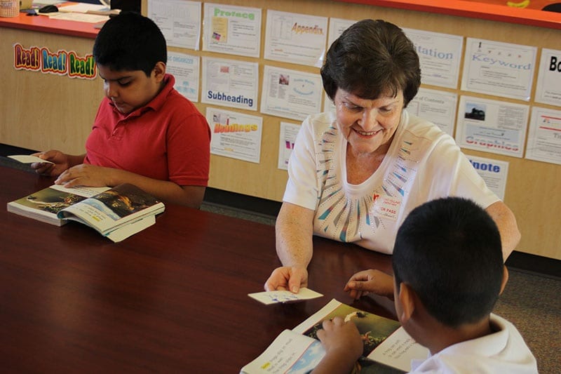 teacher smiling as students read